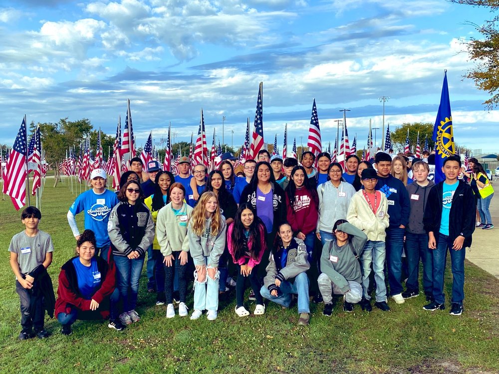 Bryan ISD students and Superintendent Ginger Carrabine posing for a photo in front of American flags