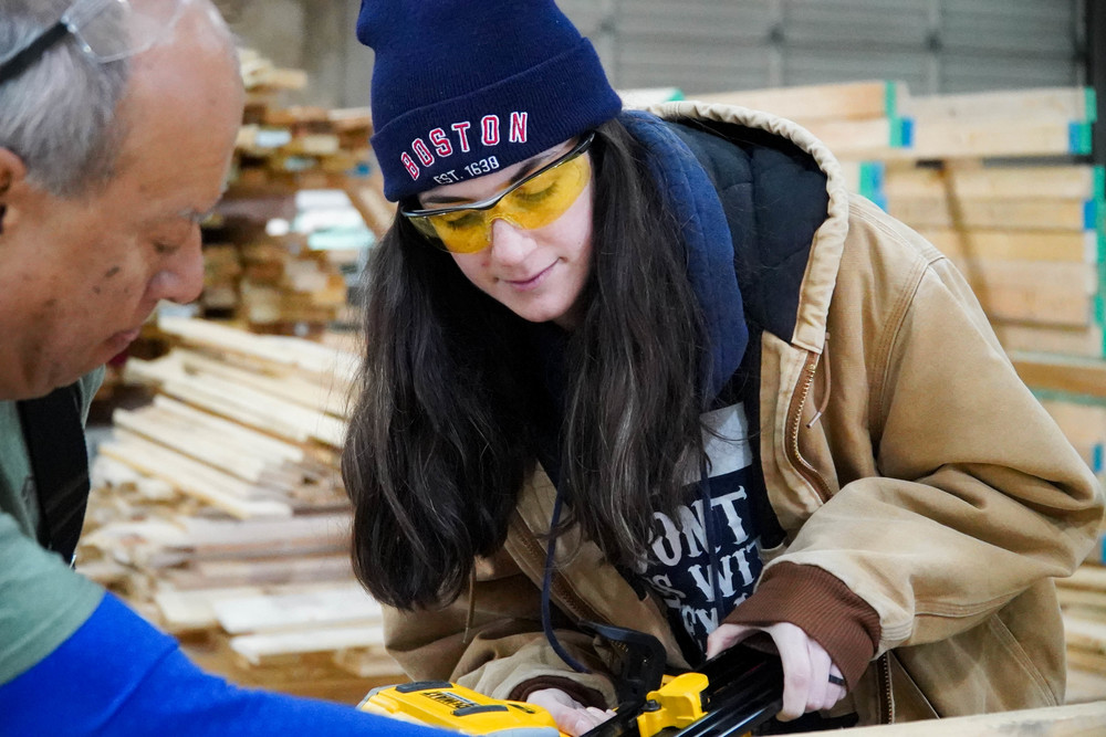 Kristen Cain uses a nail gun to build a wall