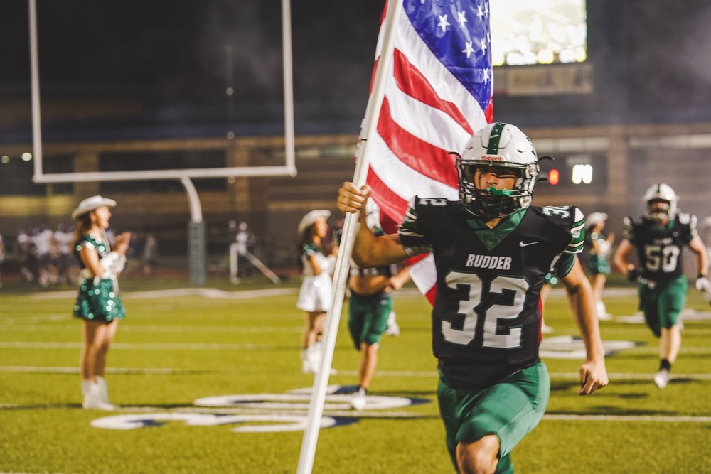 Rudder Football Player Running on to the Football Field with an American Flag