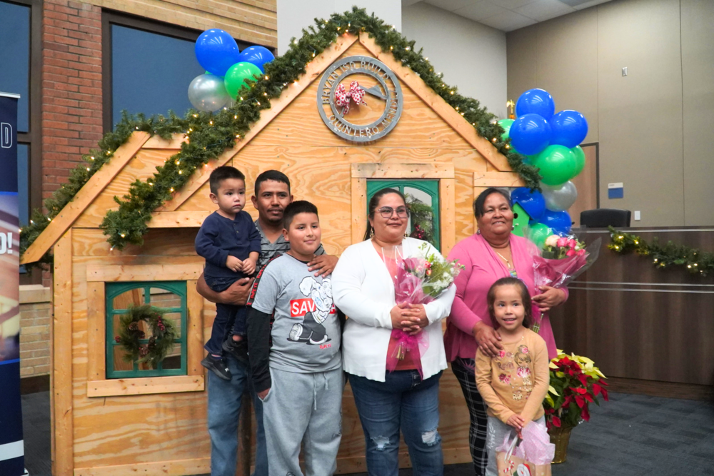 Quintero-Mendez Family in front of a Bryan ISD Build display