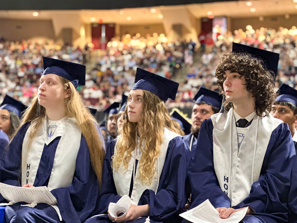 Bryan High School Graduates attend commencement in blue cap and gown and honors cords