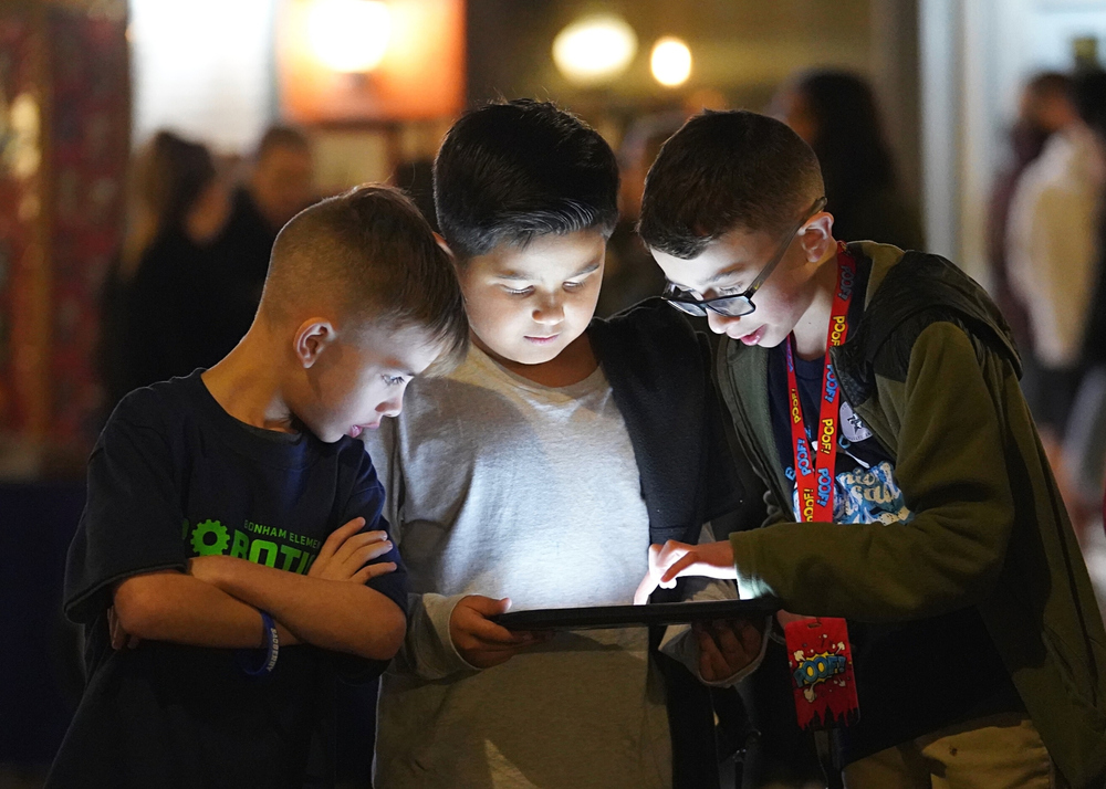 Three students looking at a tablet