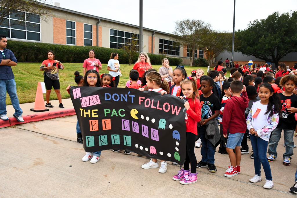 Crockett Elementary first grade students holding a sign that reads "Don't Follow the Pac. Be Drug Free" with a Pac-Man theme.