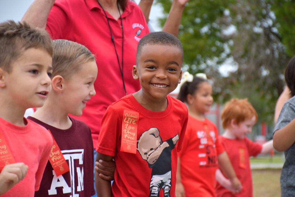 Crockett Elementary students smiling while walking in the Red Ribbon Parade