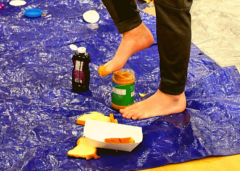 foot scooping out peanut butter from jar with foot